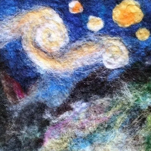 Close-up of a felted artwork depicting a starry night sky inspired by Vincent van Gogh's painting, with swirling stars and a dark, textured background.