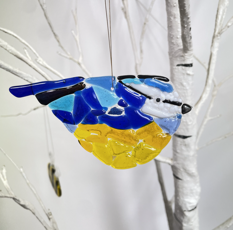 Colourful glass bird ornament hanging from white tree branches