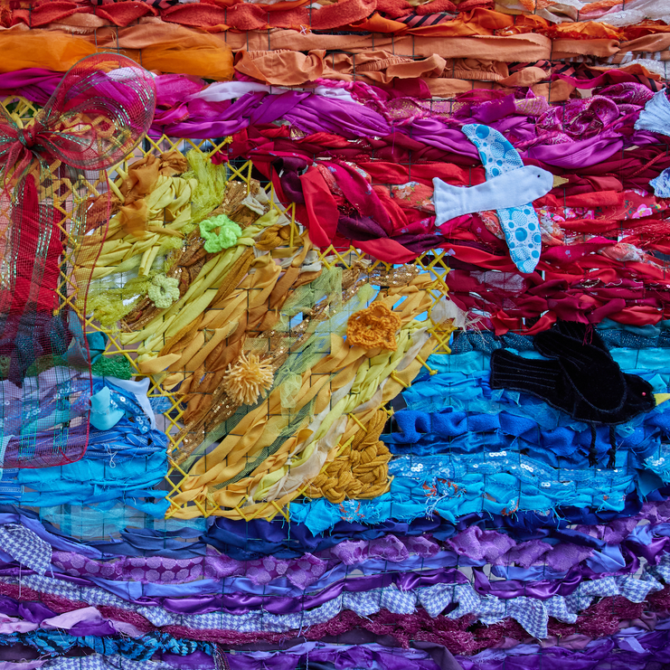 Colourful quilt made of scraps of fabric with sewn stuffed animals and decorations.