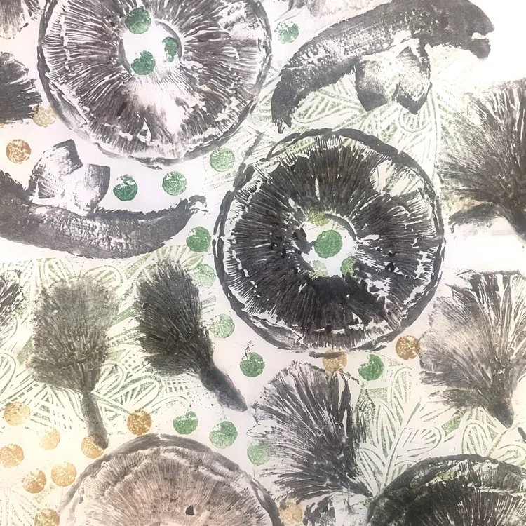 A patterned fabric with black and white sea urchins, shells, and gold and green dots.