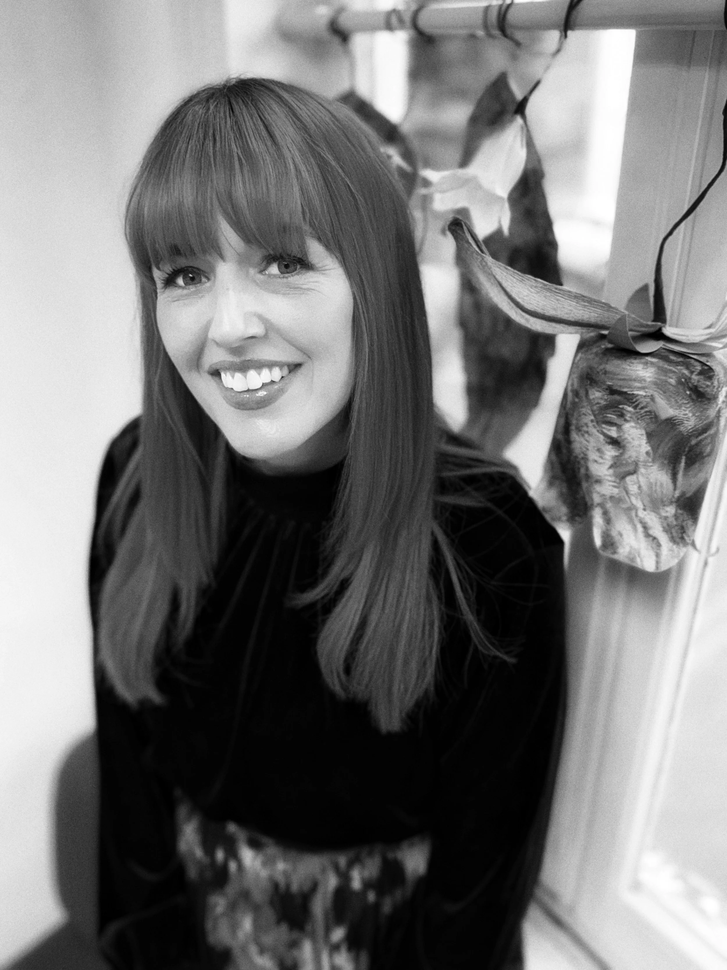 A photo of Sam Kitson with long hair wearing a flower crown, making a slight smile, in black and white.