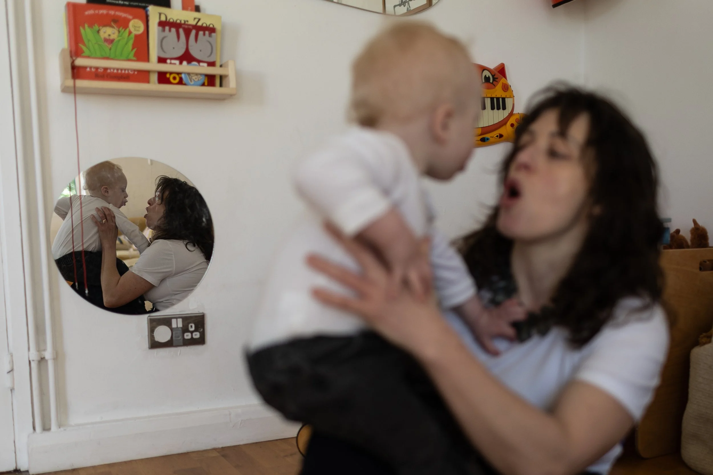 Mum with baby with their reflection in a round wall mirror a perfect family photo session in Hoxton