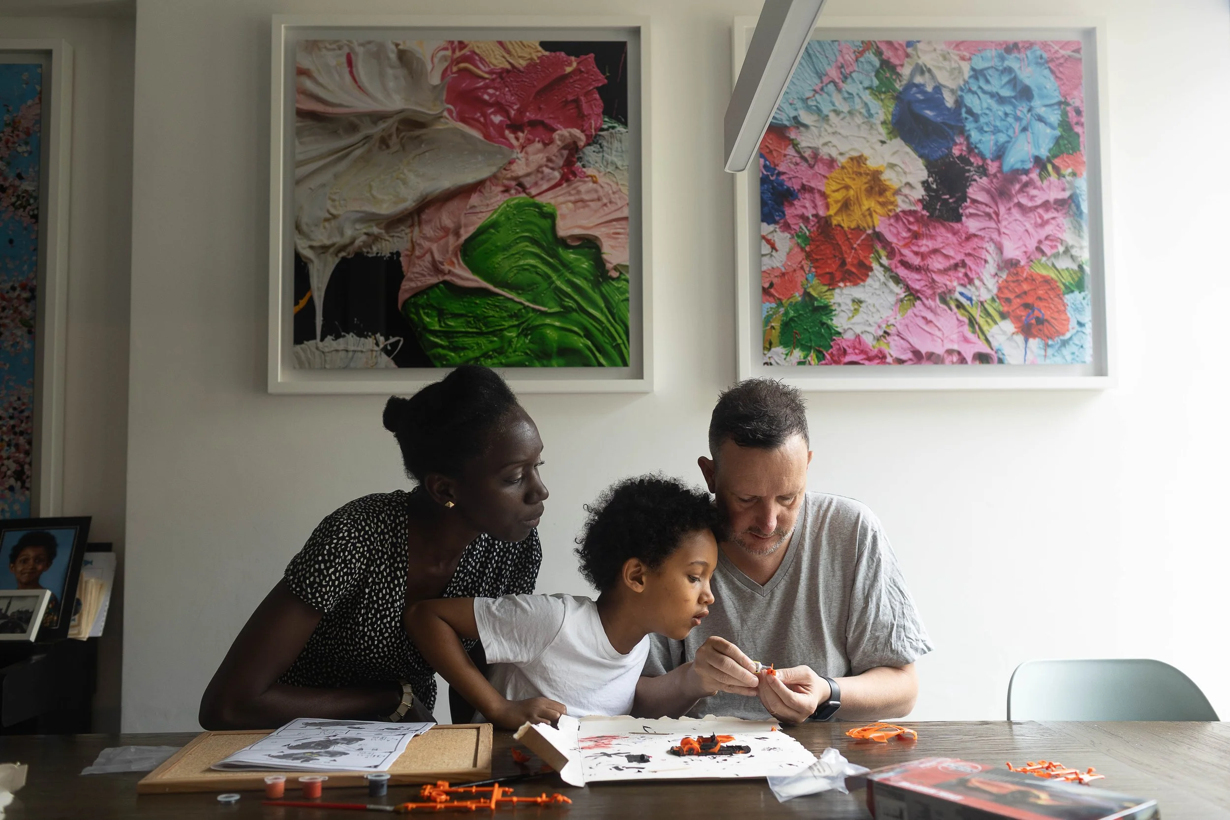 A mum and dad with their son building a model car during a family photography session with professional photographer Pollachik Photography in Islington North London