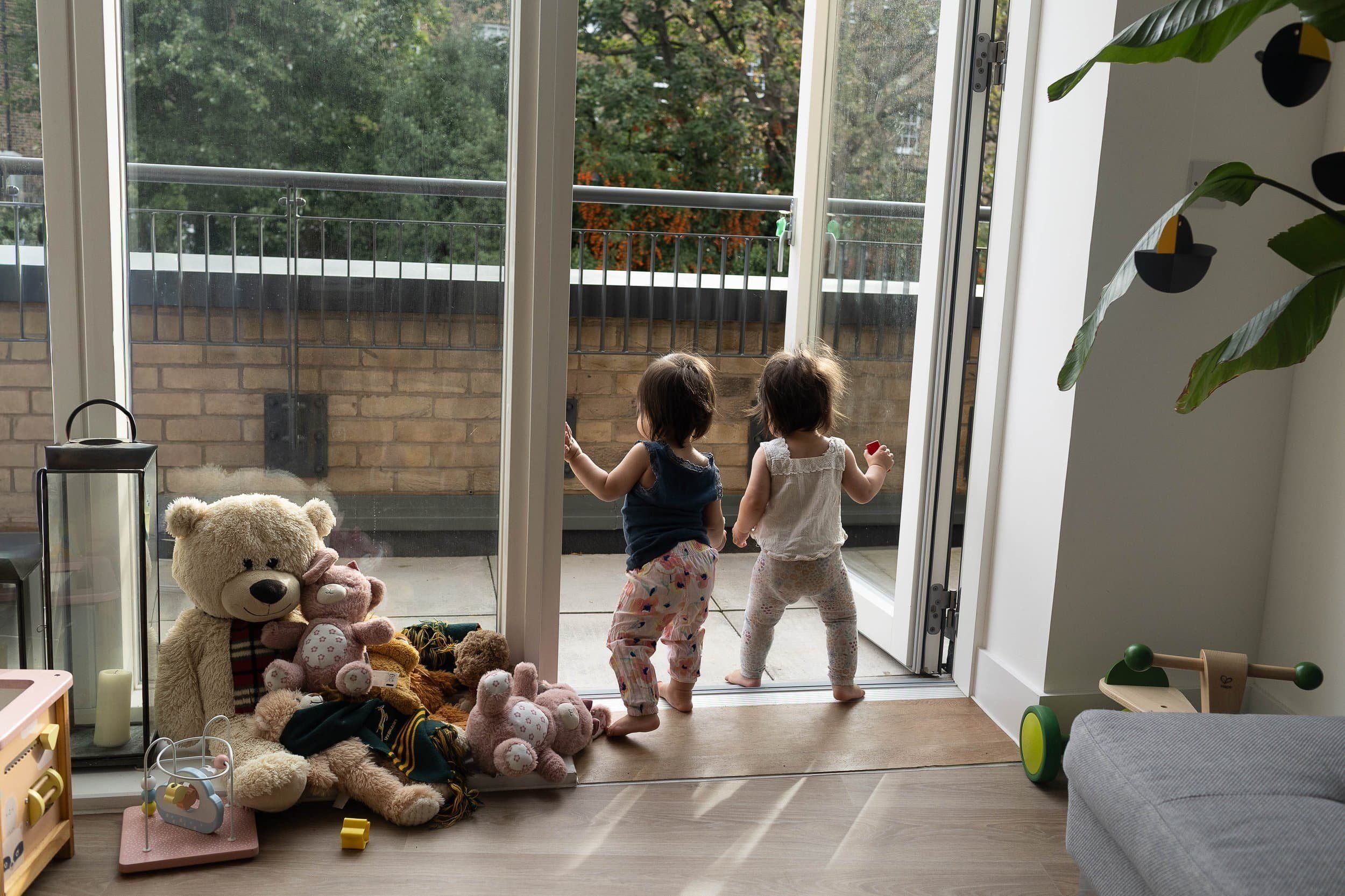 Twin toddlers looking walking towards the balcony during a family photo shoot in Highbury