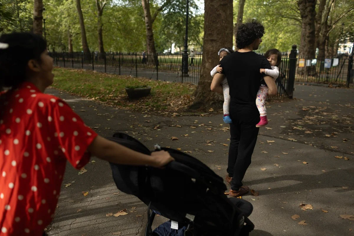Twin toddlers being carried by the dad in Highbury Fields