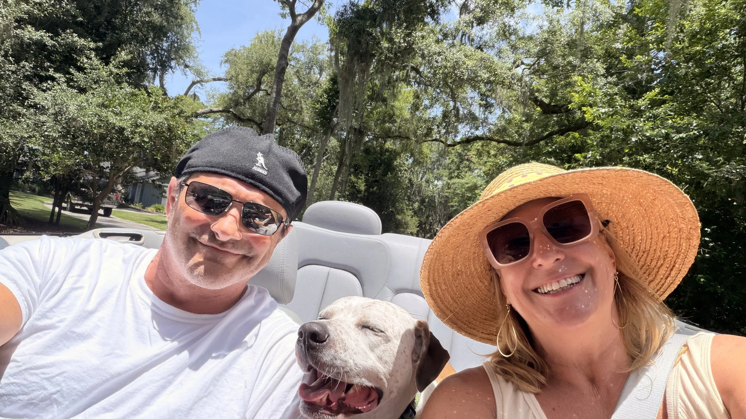 woman and man riding in a convertible with a dog on st simons