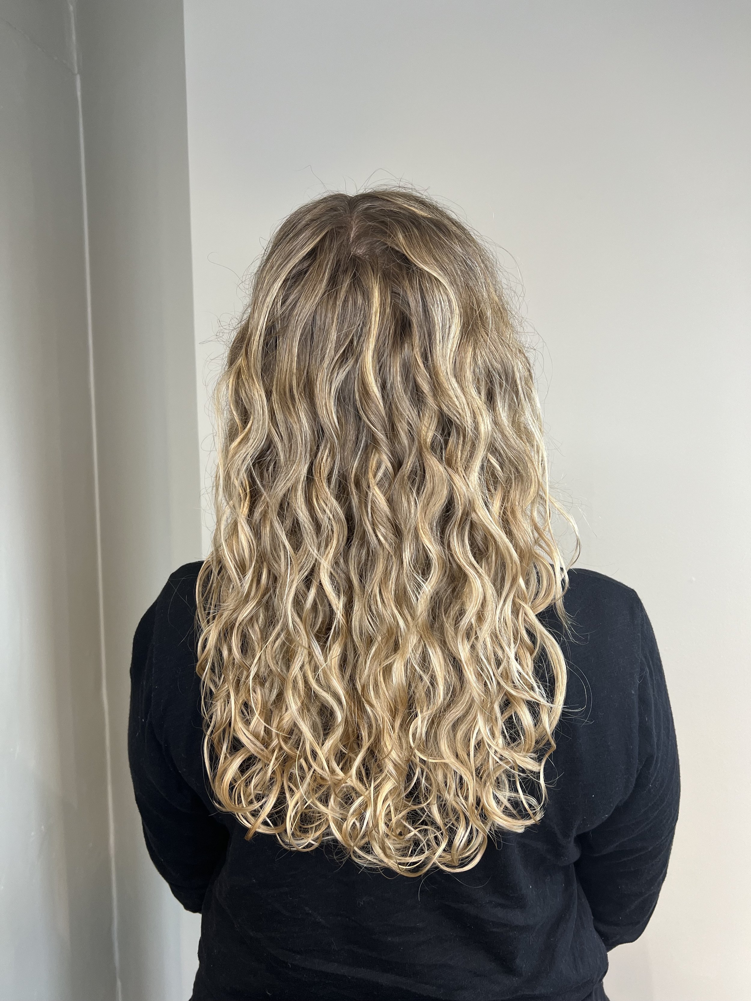 Woman with blonde highlights created by a hand painted balayage technique.