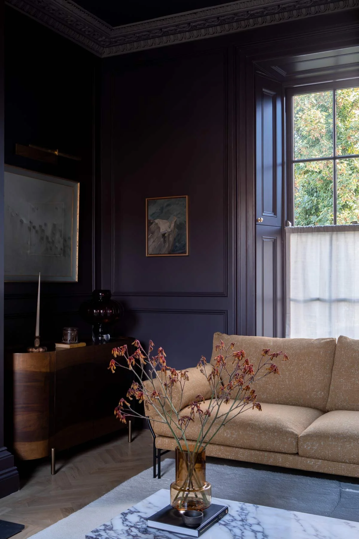 Living room with dark purple wood panelled walls, a sofa and a coffee table in the foreground