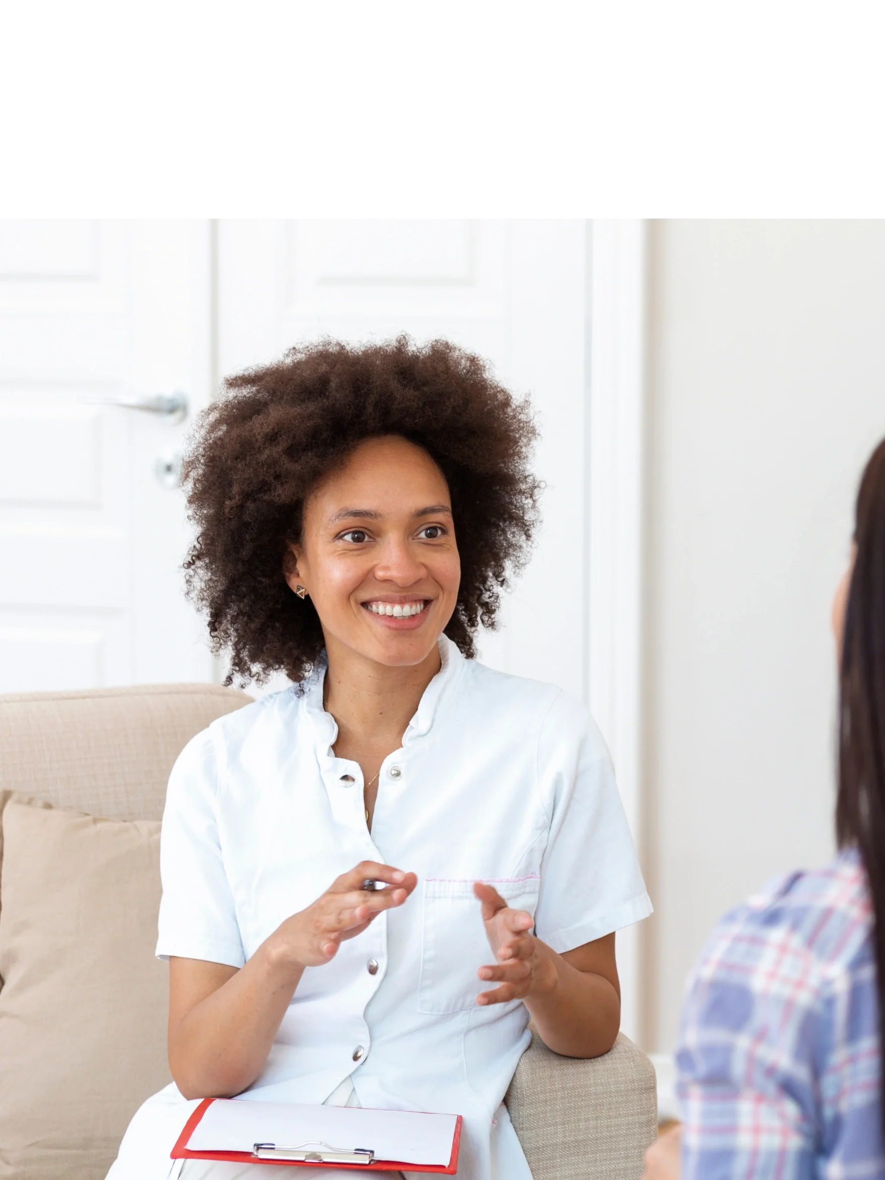 A woman with curly hair smiling and talking to another person in a professional setting.