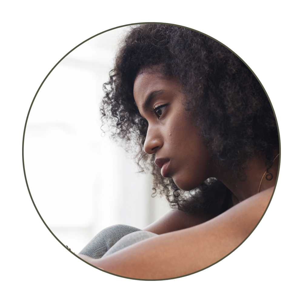 Close-up of a young woman with curly hair looking down thoughtfully.