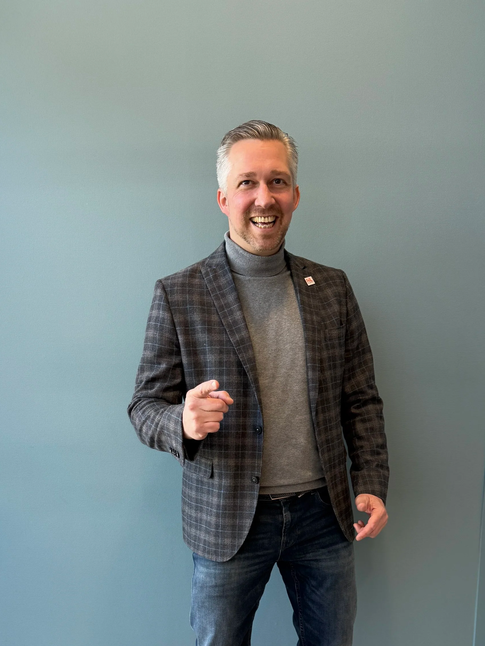 Man in een blazer houdt een robot vast met een displayhoofd met blauwe ogen en een grote glimlach.