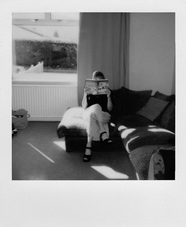 Polaroid of a woman sitting on a sofa reading a magazine in soft natural light, part of an ED recovery quote series.