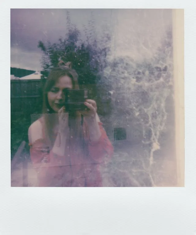 Polaroid of a woman in a pink top reflected in glass, holding a camera. Part of an ED recovery quote series on vulnerability.
