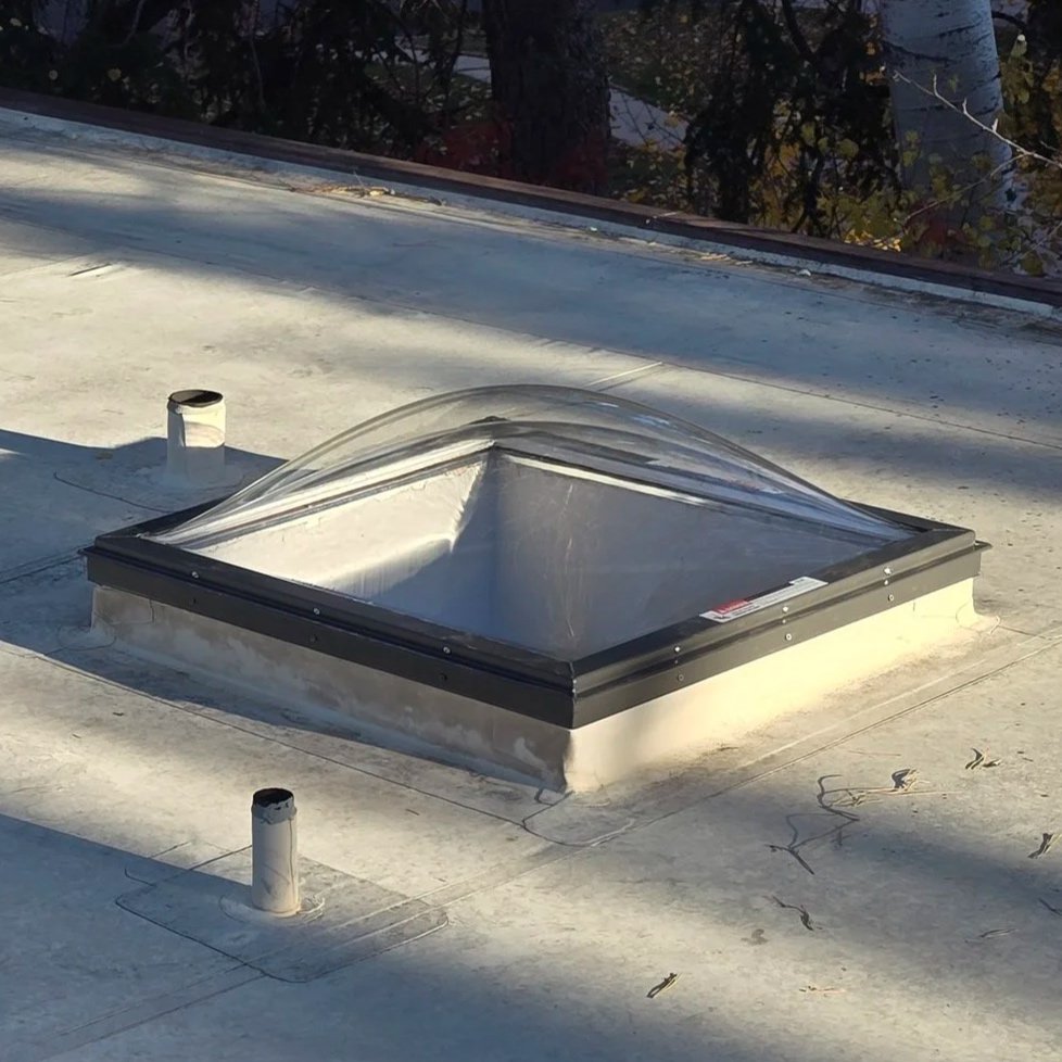 An acrylic dome skylight installed on a flat roof.