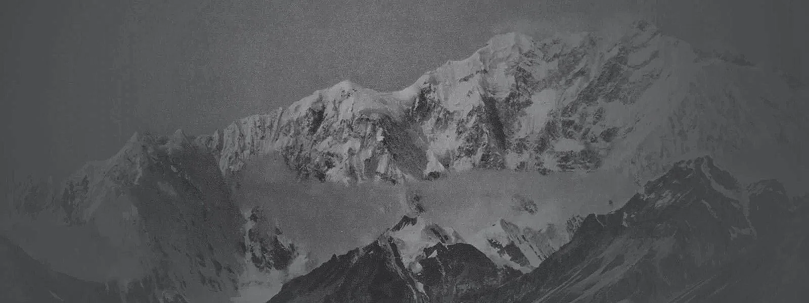 Snow-covered mountain peaks under a cloudy sky.
