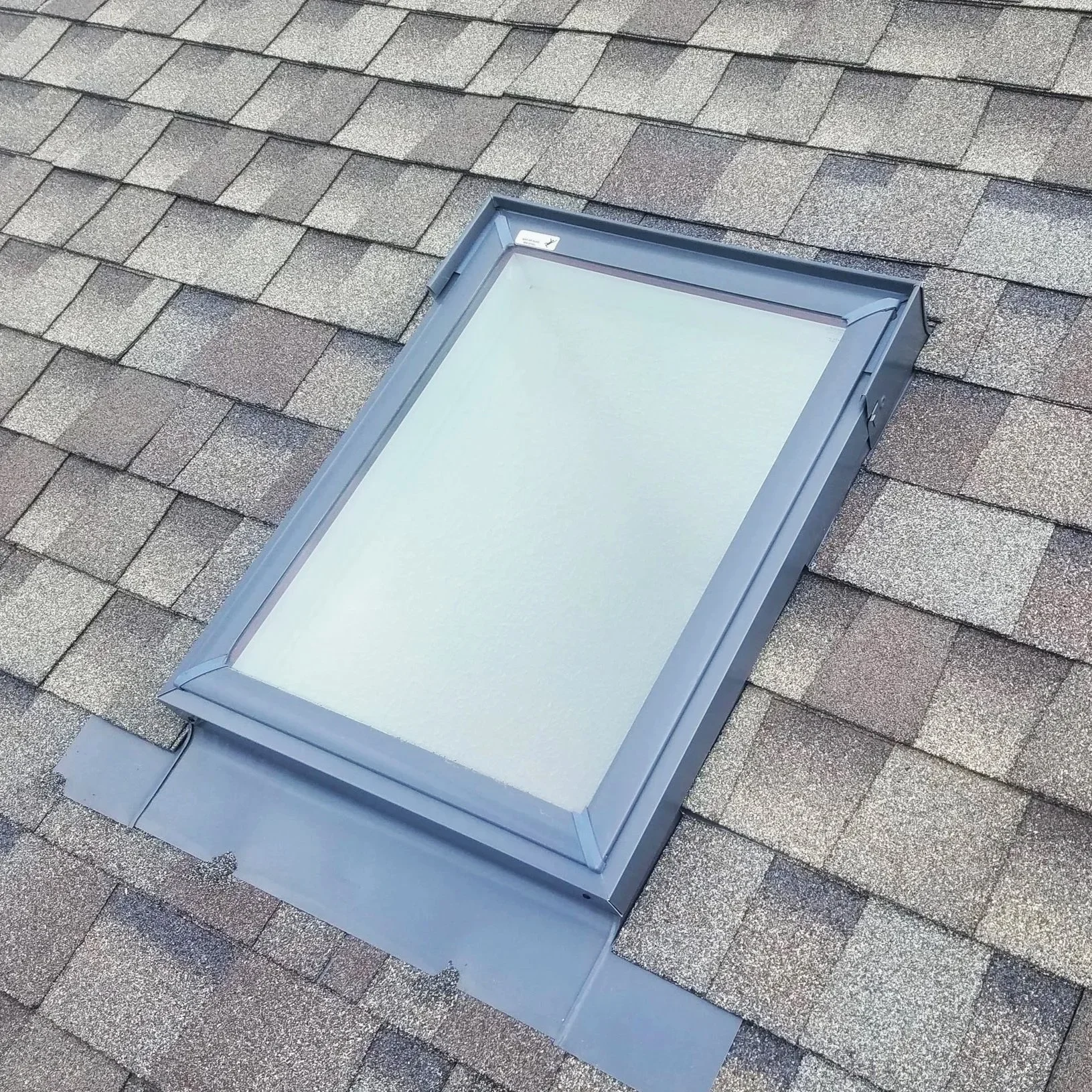 A Velux Fixed Deck-Mounted Skylight installed on an asphalt shingle roof.