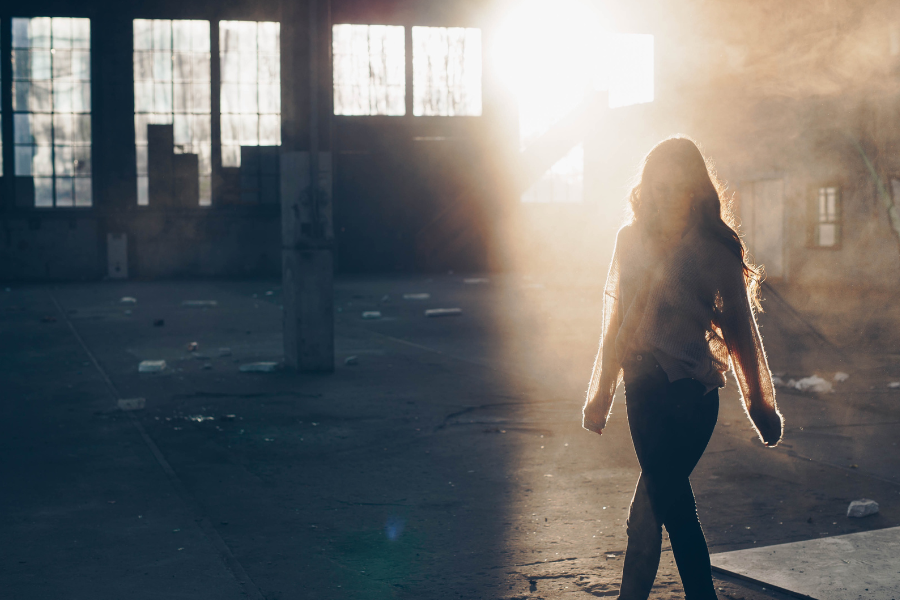 Woman walking through warehouse with the sun in the background.