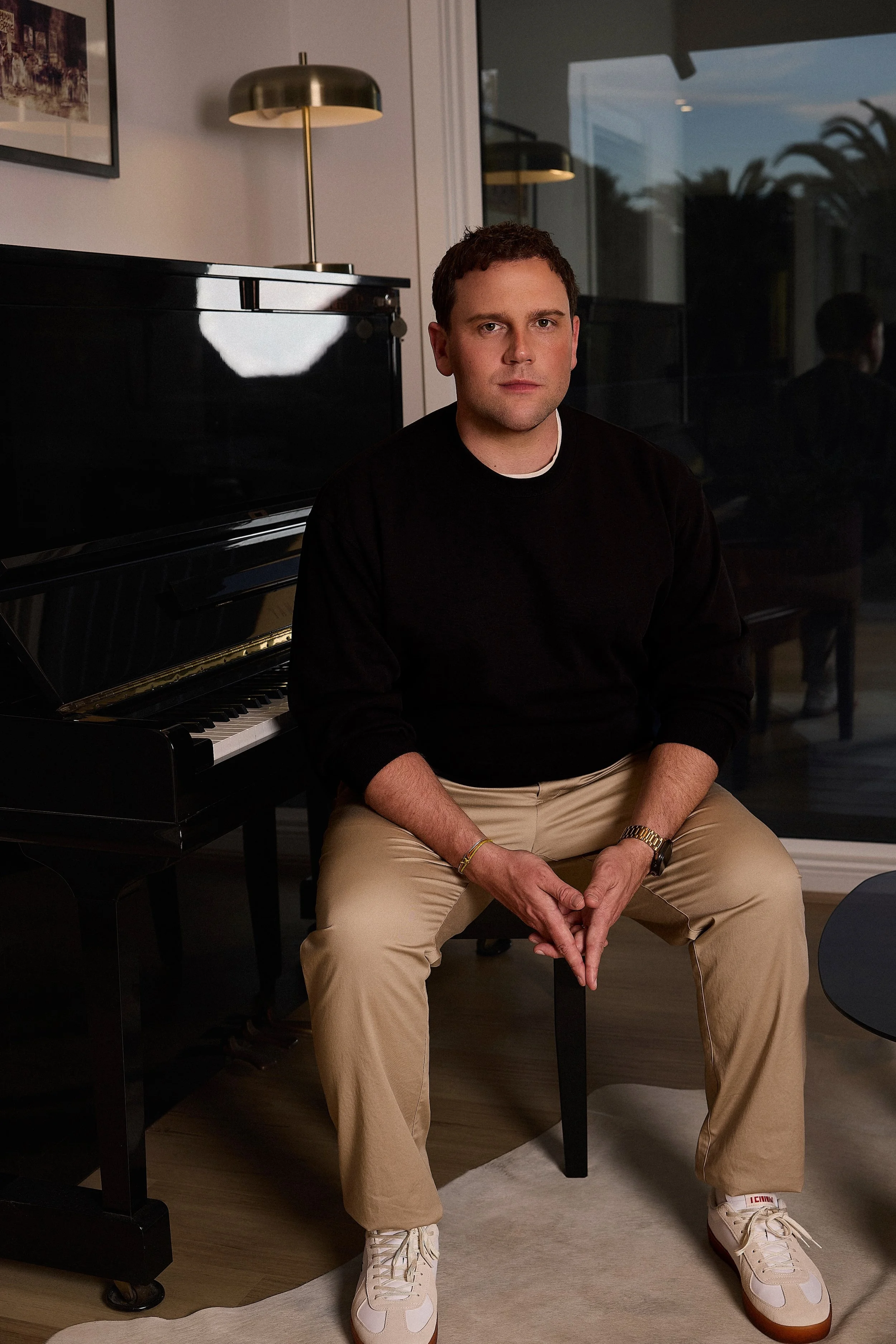 Portrait of Josh Simons, entrepreneur and CEO of Vinyl Group, seated beside a piano.