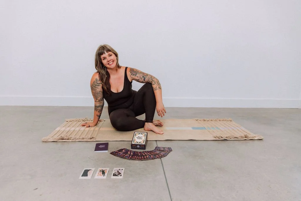 Sarah Jane seated cross-legged on a yoga mat with tarot cards in front of her