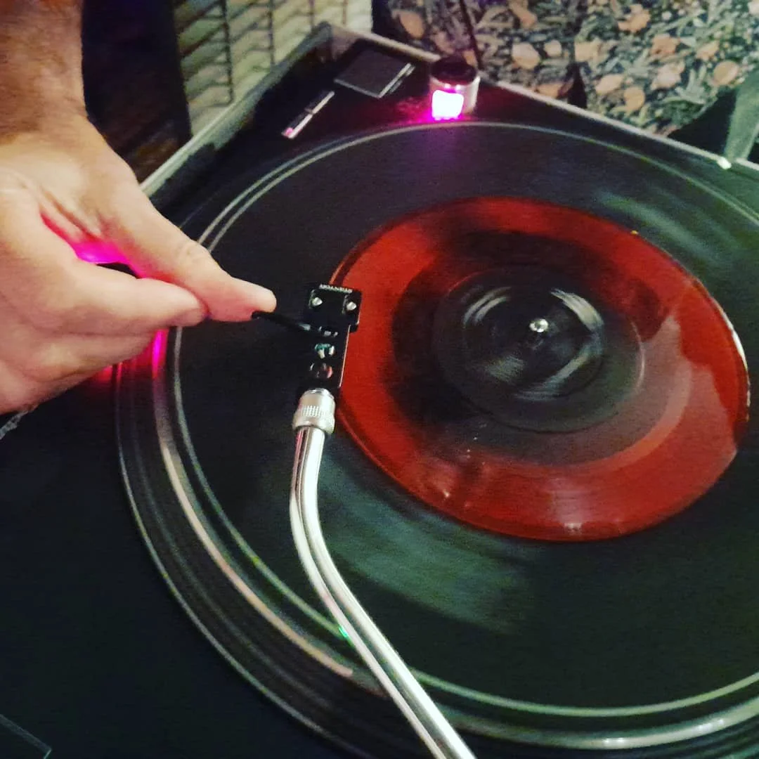 fingers placing needle on a record