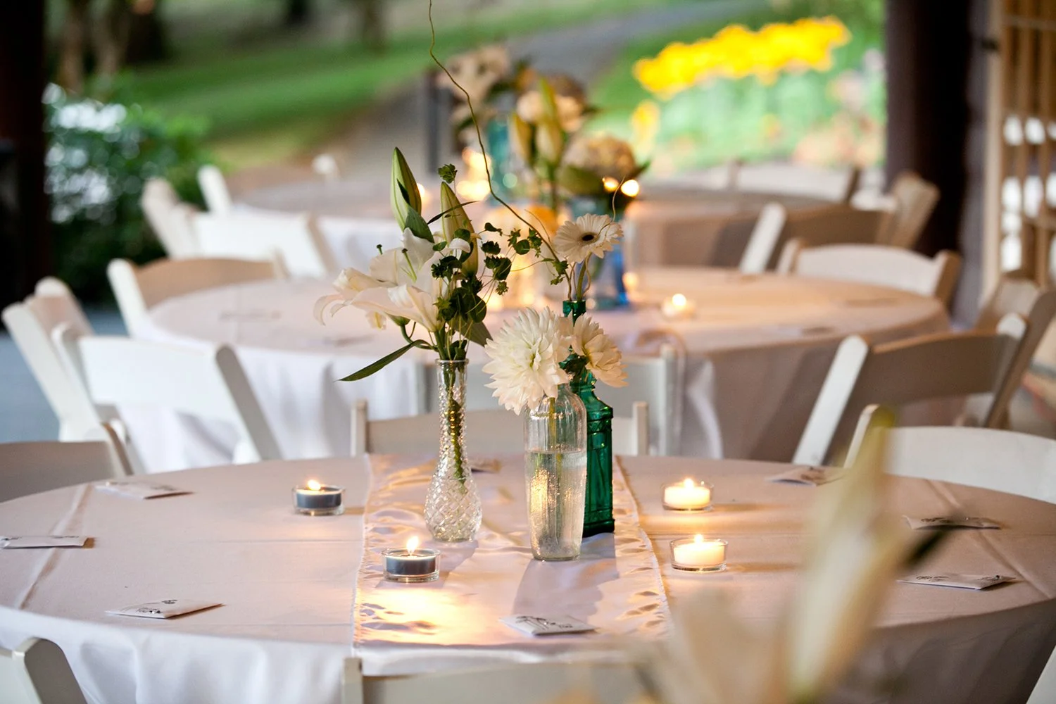 Runde bord dekket til sommerfest med levende lys og blomster