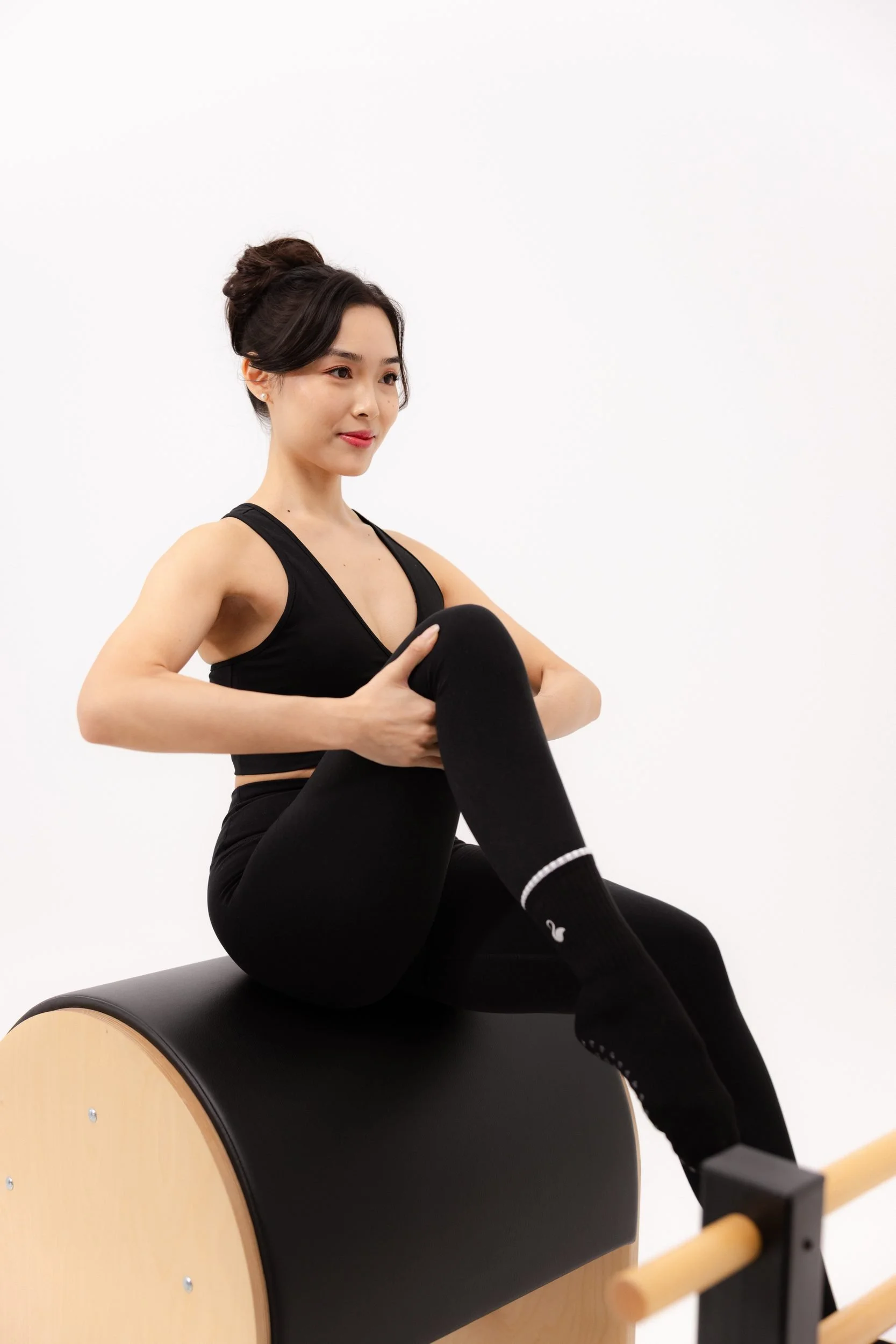 Seated hip and glute stretch on the Pilates ladder barrel