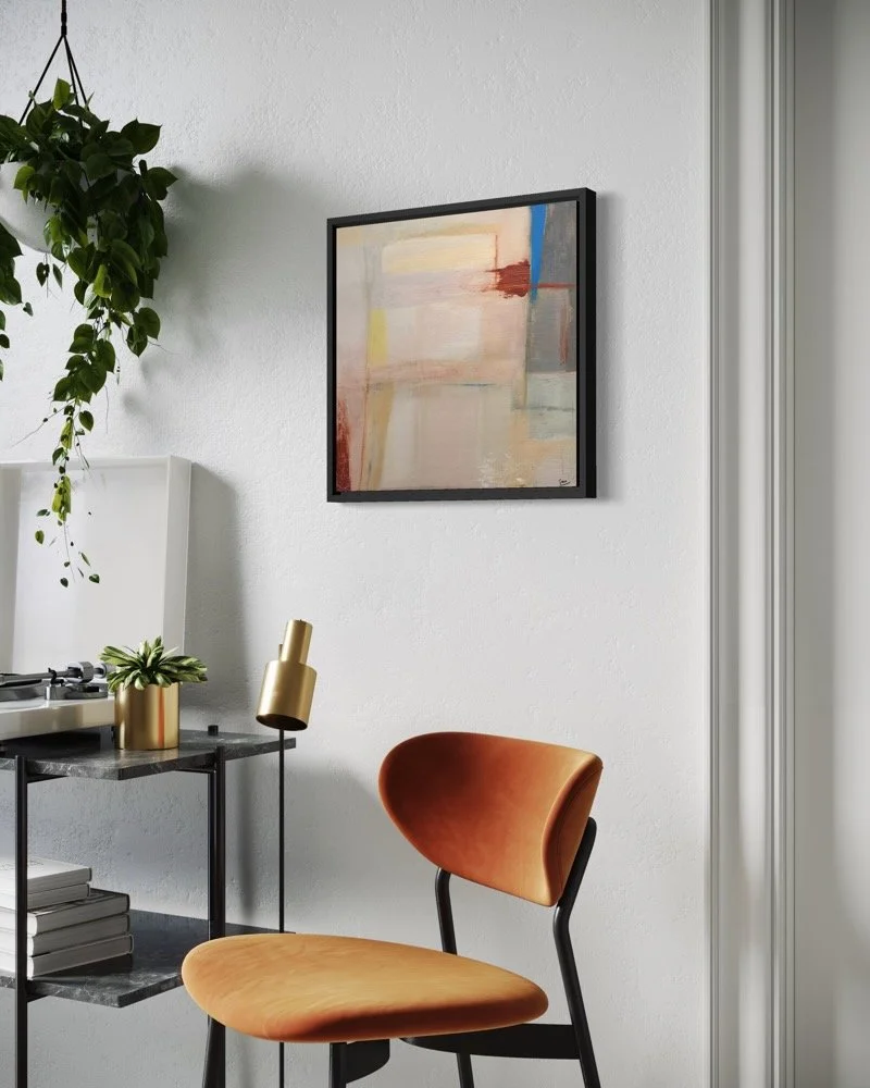 Peripheral Heat, abstract painting by Gera Dunachie in a black frame, displayed above a black console beside an orange chair and hanging plant in a contemporary interior.
