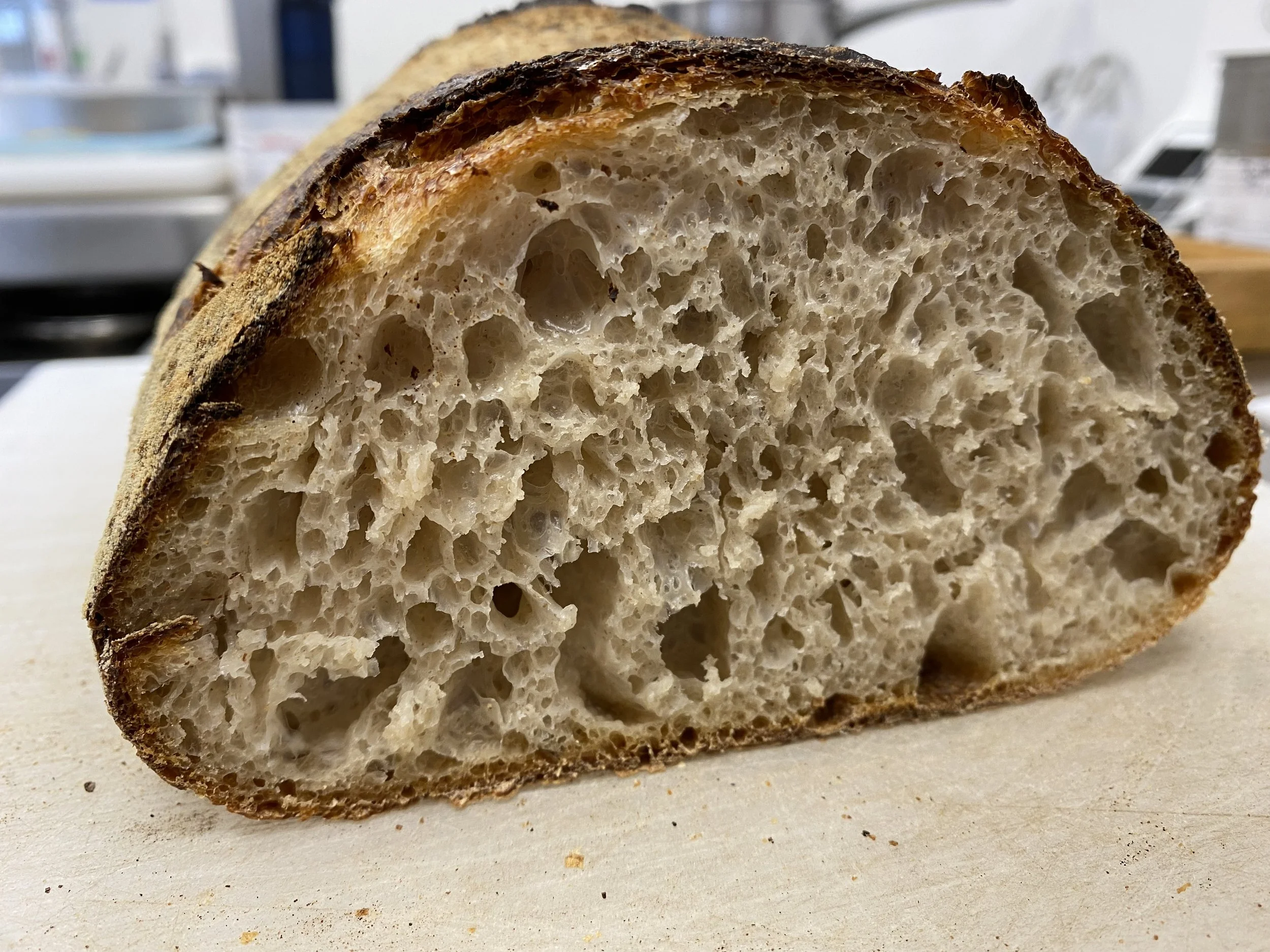 Close-up of a sliced loaf of artisan sourdough bread showing a chewy crust and airy crumb.