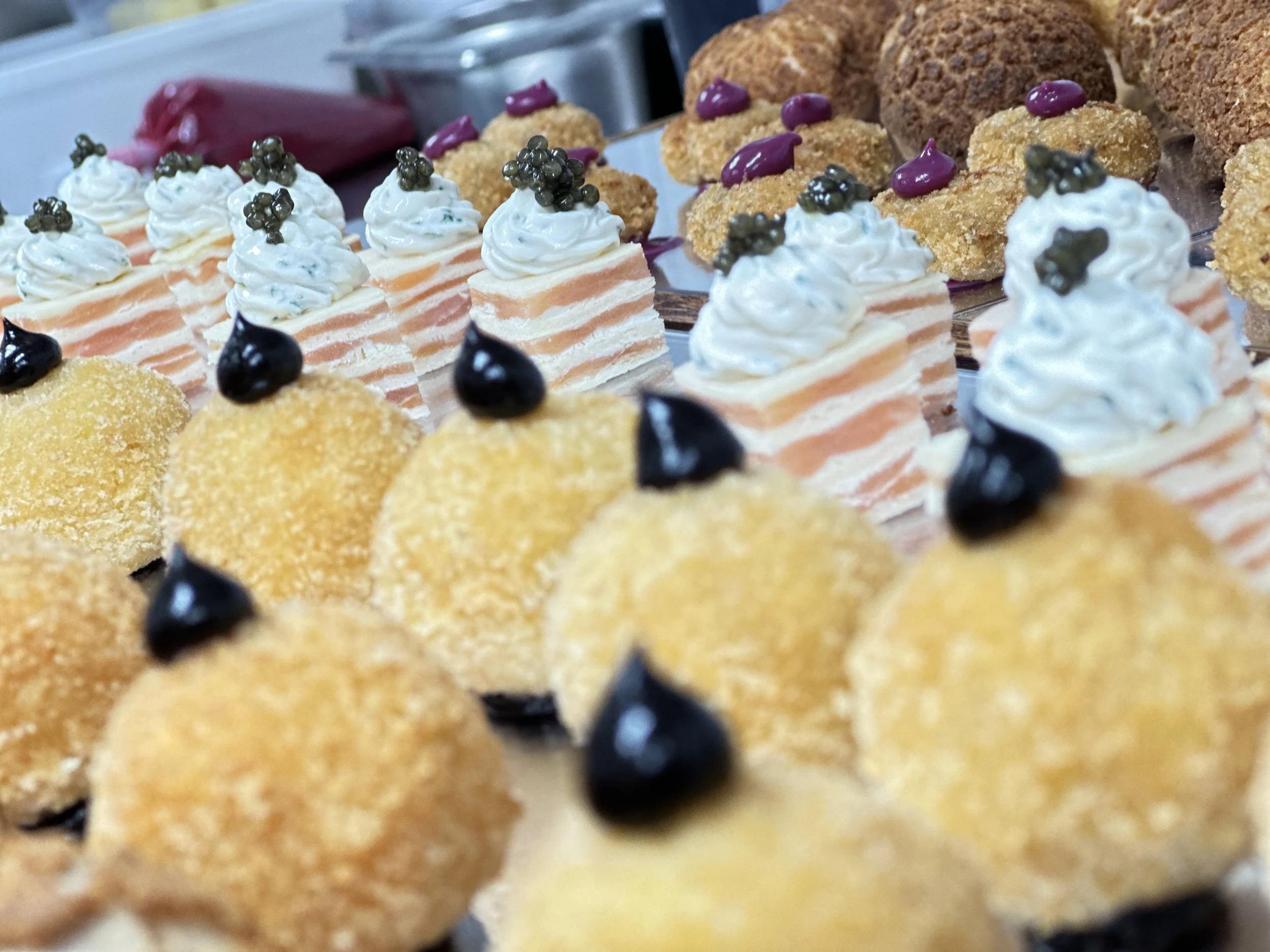 Assorted canapés, of arancini, salmon roulade layer and topped with caviar on a serving board