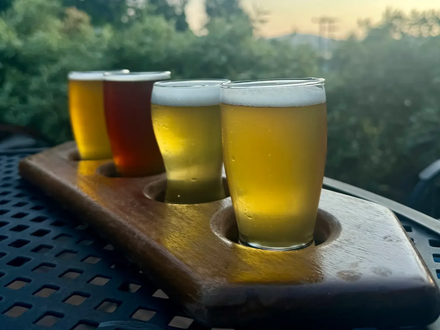 flight of beer on table with sunset in background