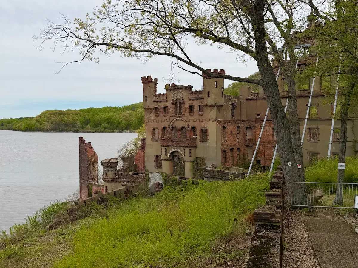 The ruins of the Bannerman Castle on a lush green island surrounded by the Hudson River.
