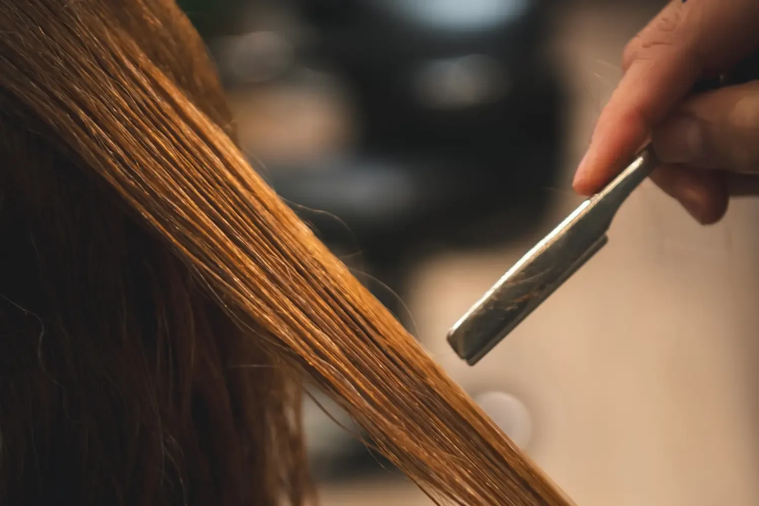 hair stylist cutting red long hair with a razor