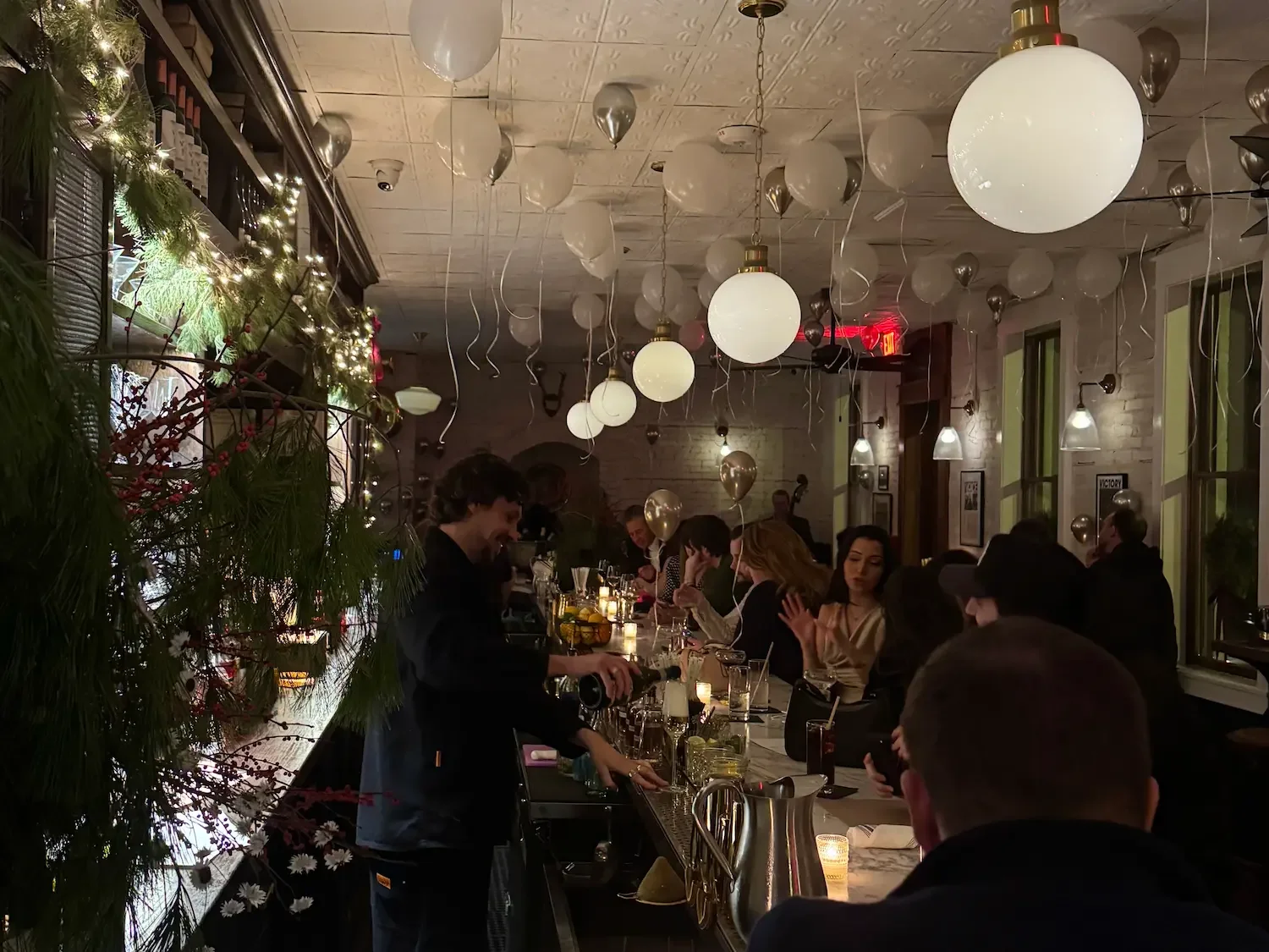 a softly lit Beacon bar is filled with people and balloons for New Year's Eve celebrations.