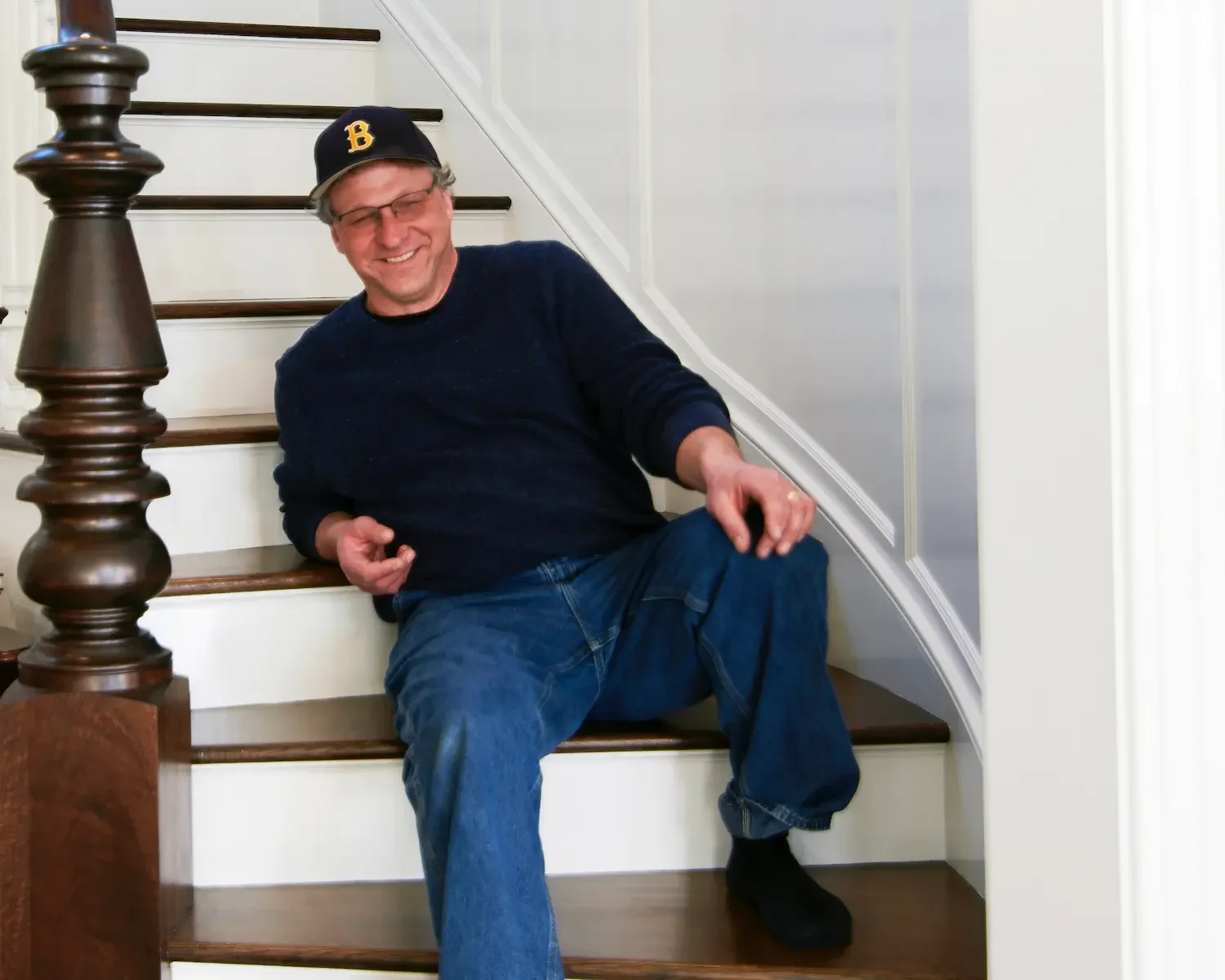 serge young sits smiling on a wooden staircase