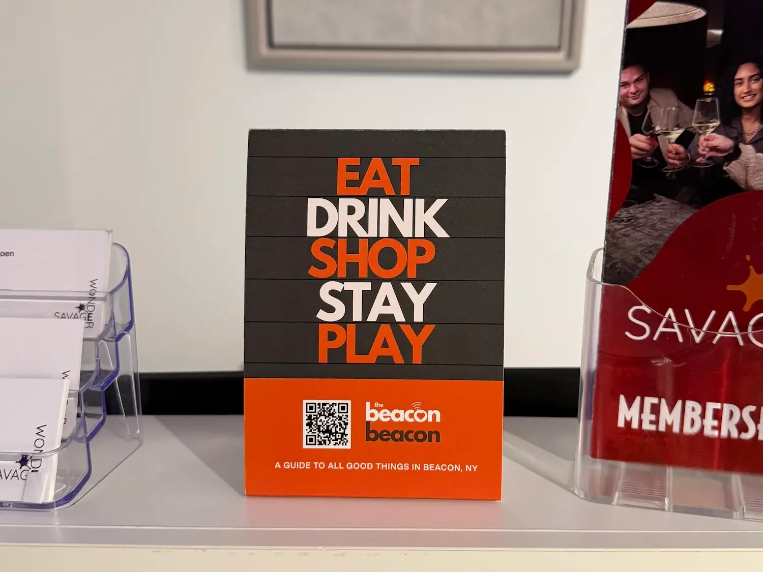 a countercard promoting The Beacon Beacon sits on the reception desk at Savage Wonder Arts Center