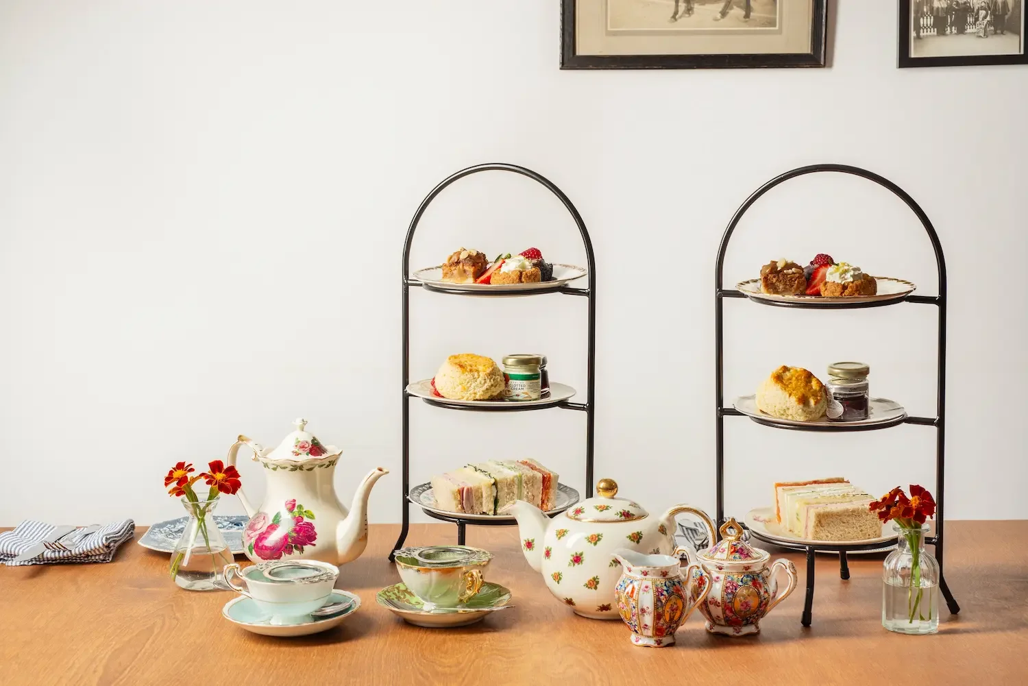 An afternoon tea spread with scones, sandwiches, cakes and vintage teapots and crockery