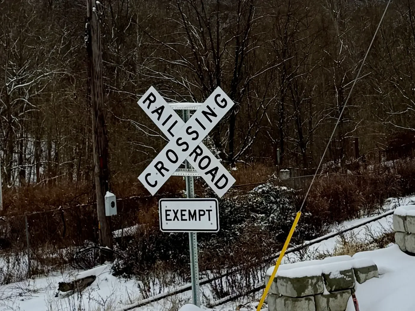railway crossing sign sits beside disused railtracks in winter