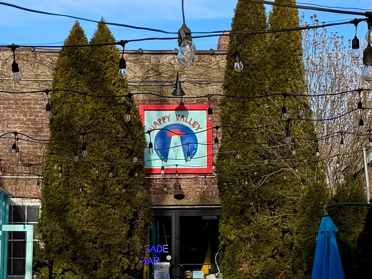 two tall trees flank a building with sign that says Happy Valley in Beacon