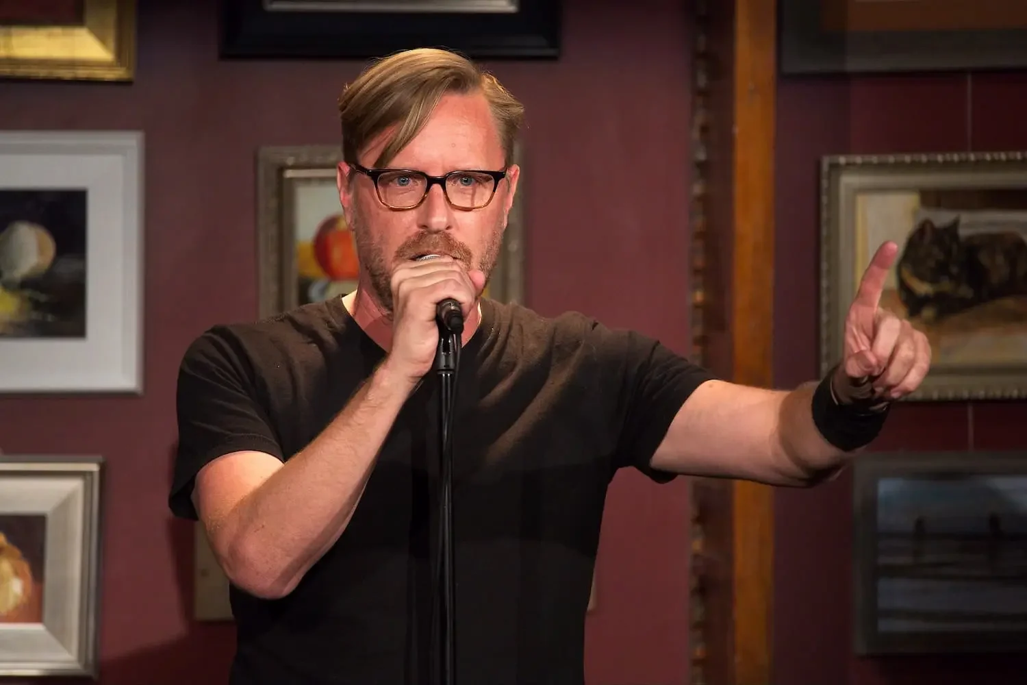 man speaks into microphone at arts venue