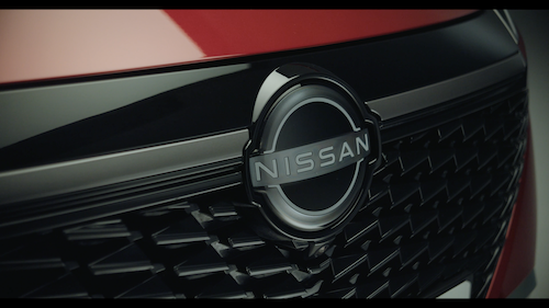 Close-up of a Coca-Cola can with condensation against a red background.