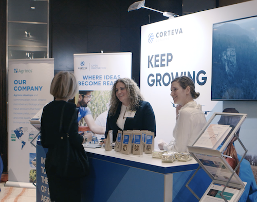 Speaker presenting on stage at a corporate event with a large screen behind them.