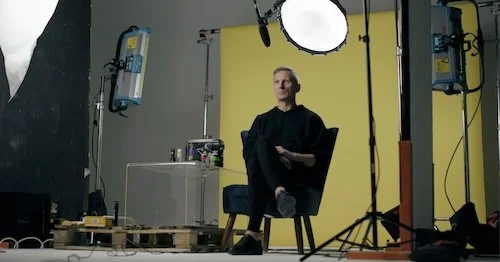 Modern wooden house with glass doors, stone pathway and mountain backdrop.