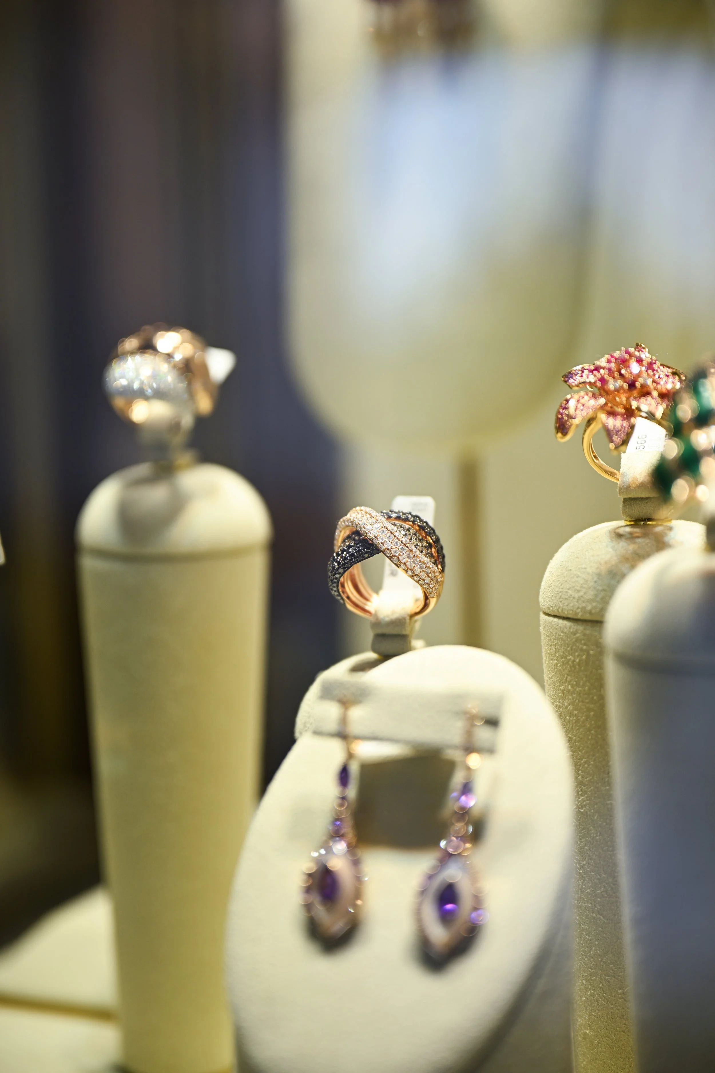Jewelry display with rings and earrings showcased on beige stands in a store.