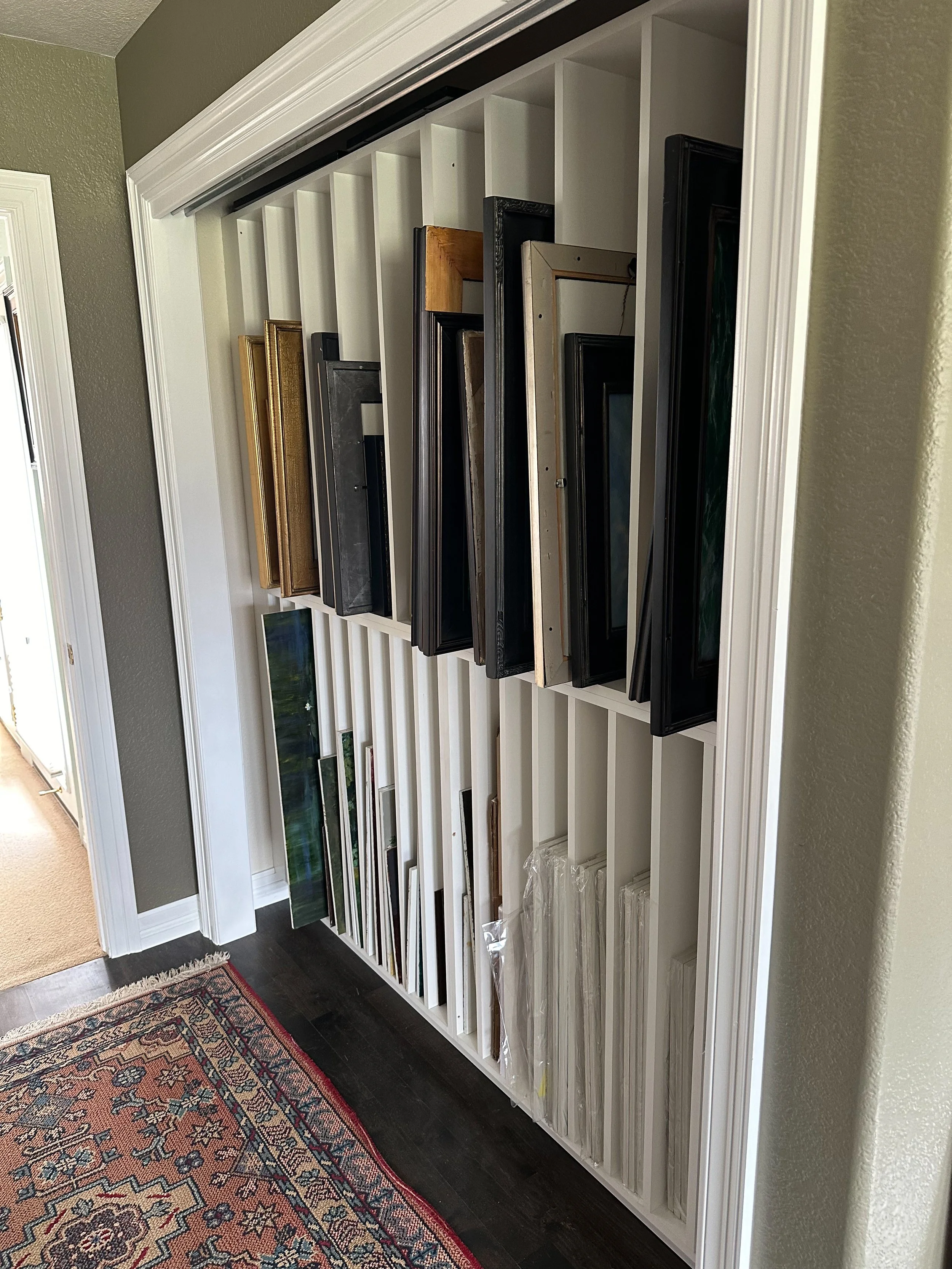 Display rack with various picture frames organized by size and color in a home interior.
