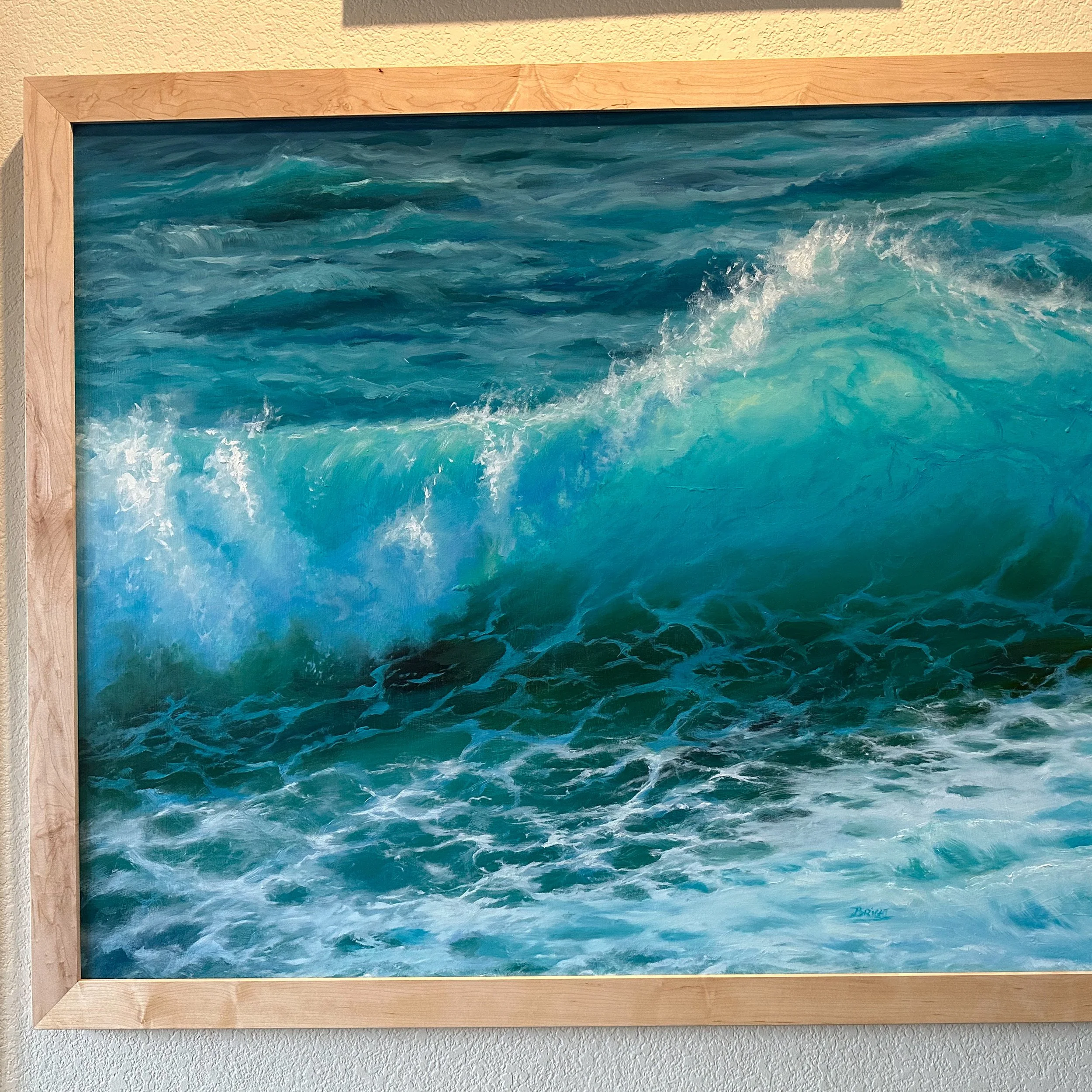 Painting of ocean waves crashing with blue and green hues, framed in light wood.