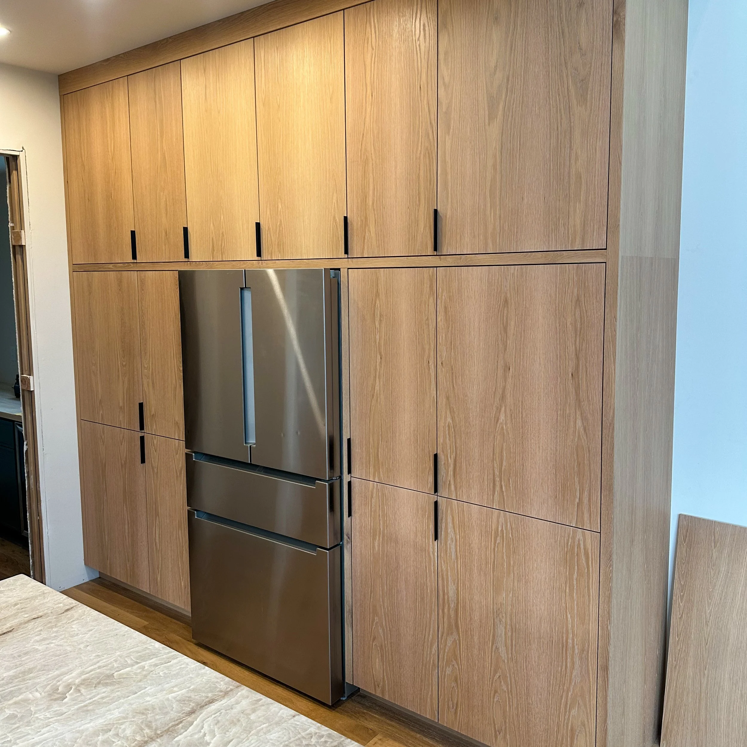 Built-in wooden cabinets surrounding a stainless steel refrigerator in a modern kitchen.