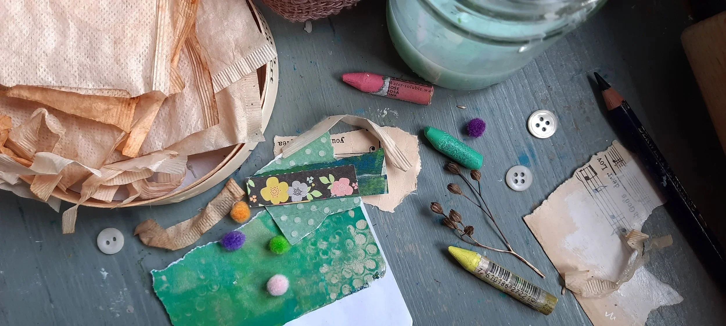 Close-up of random bits of art materials like buttons, crayons, different types of
scraps of paper and tiny colourful pompoms.