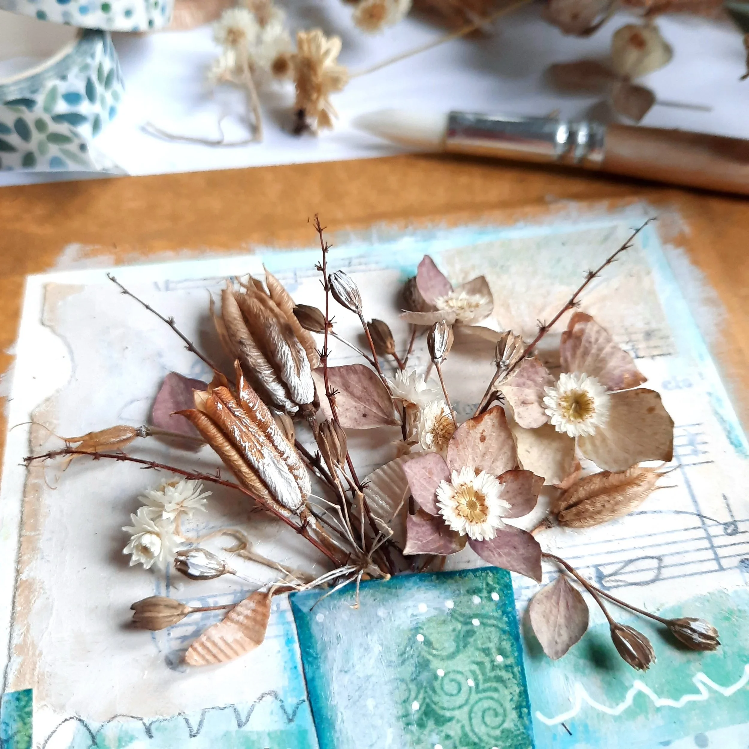 Close-up of a collage of a bouquet in a vase made from different papers and 3D dried botanical elements.