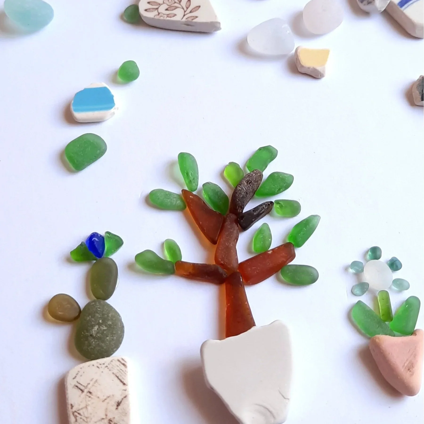 Close-up of a collage made from collected sea glass and bit of ceramics to represent indoor potted plants.