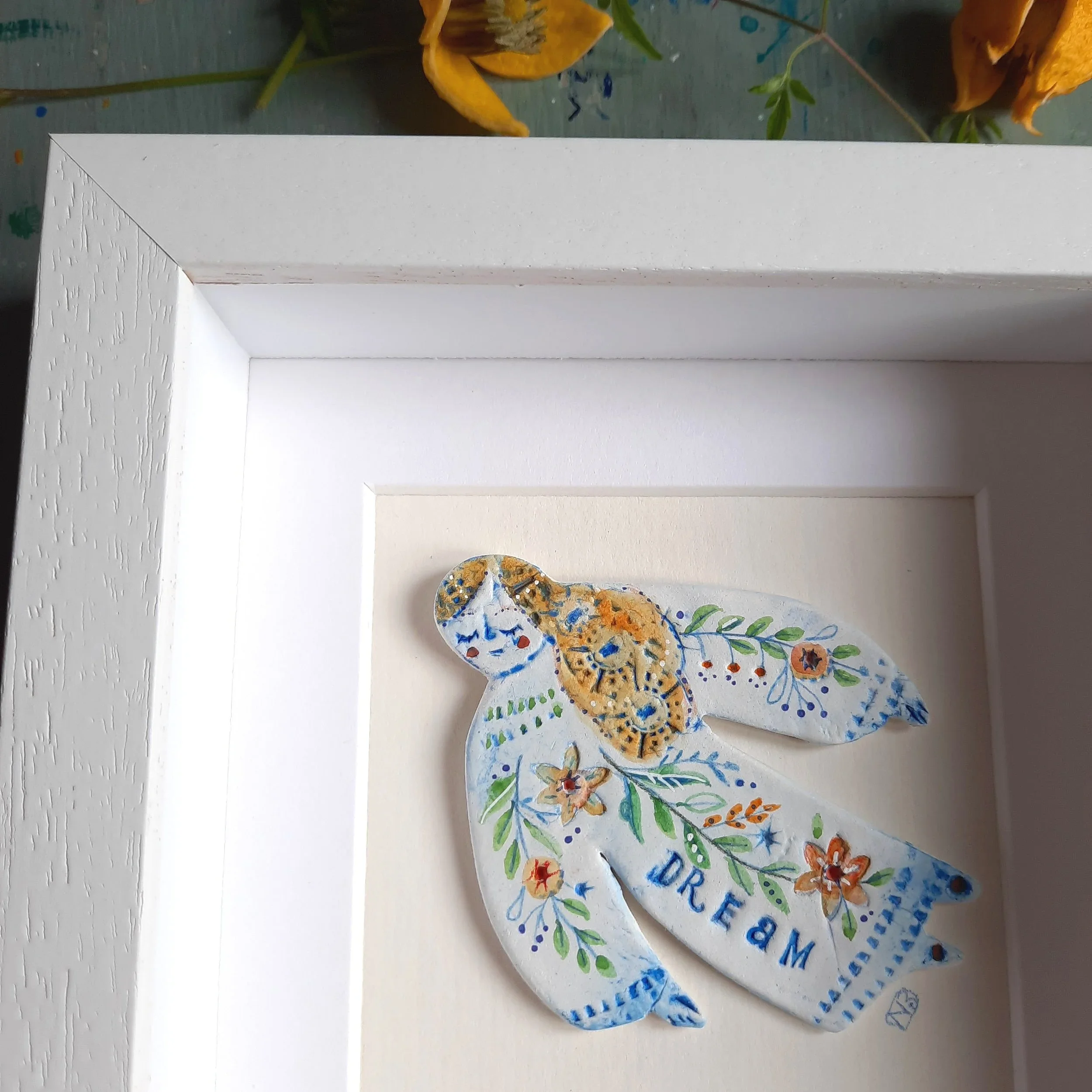 Detail of a picture of a flying clay figure in a frame.